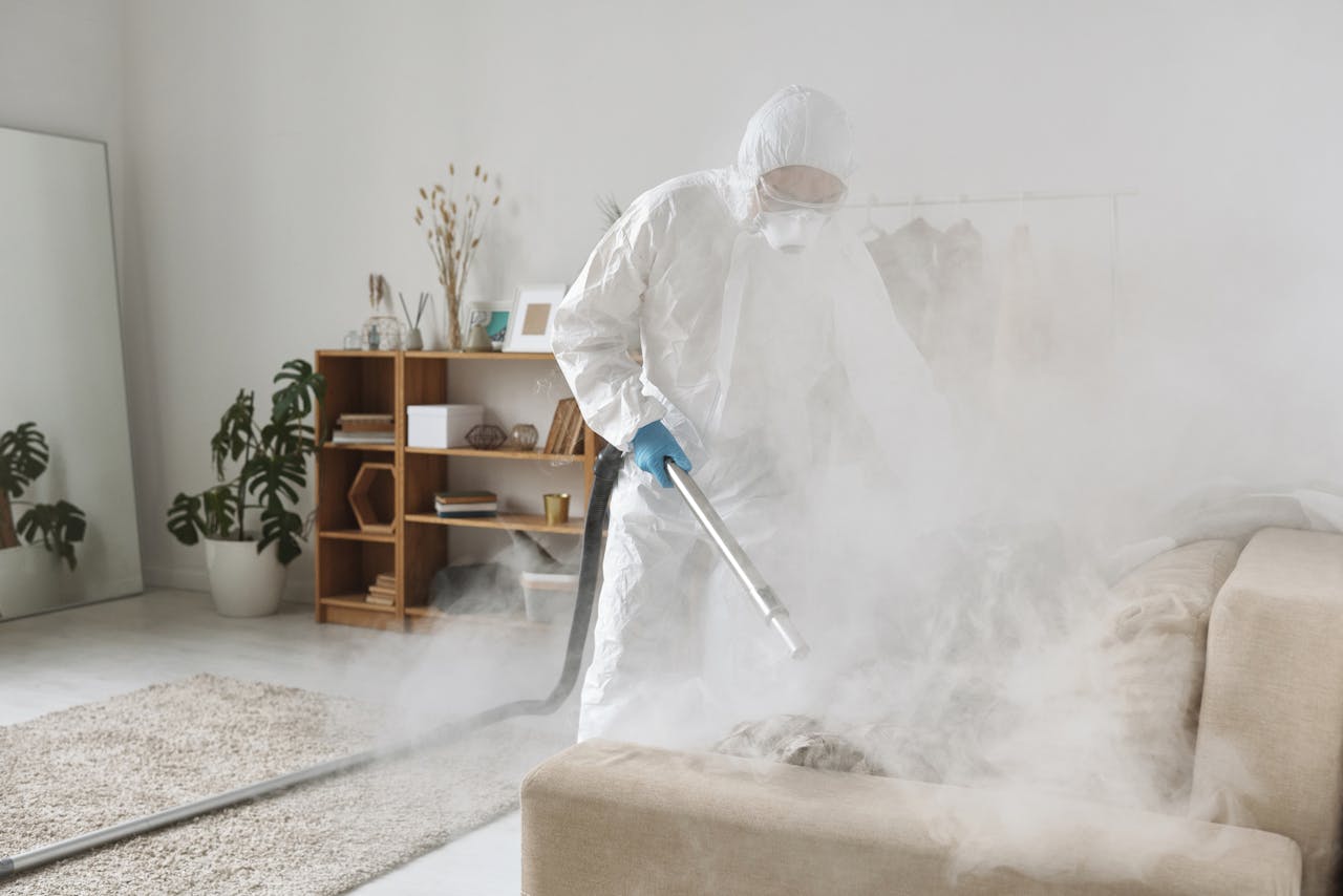 A person in PPE fumigates a living room for disinfection, ensuring safe environment.