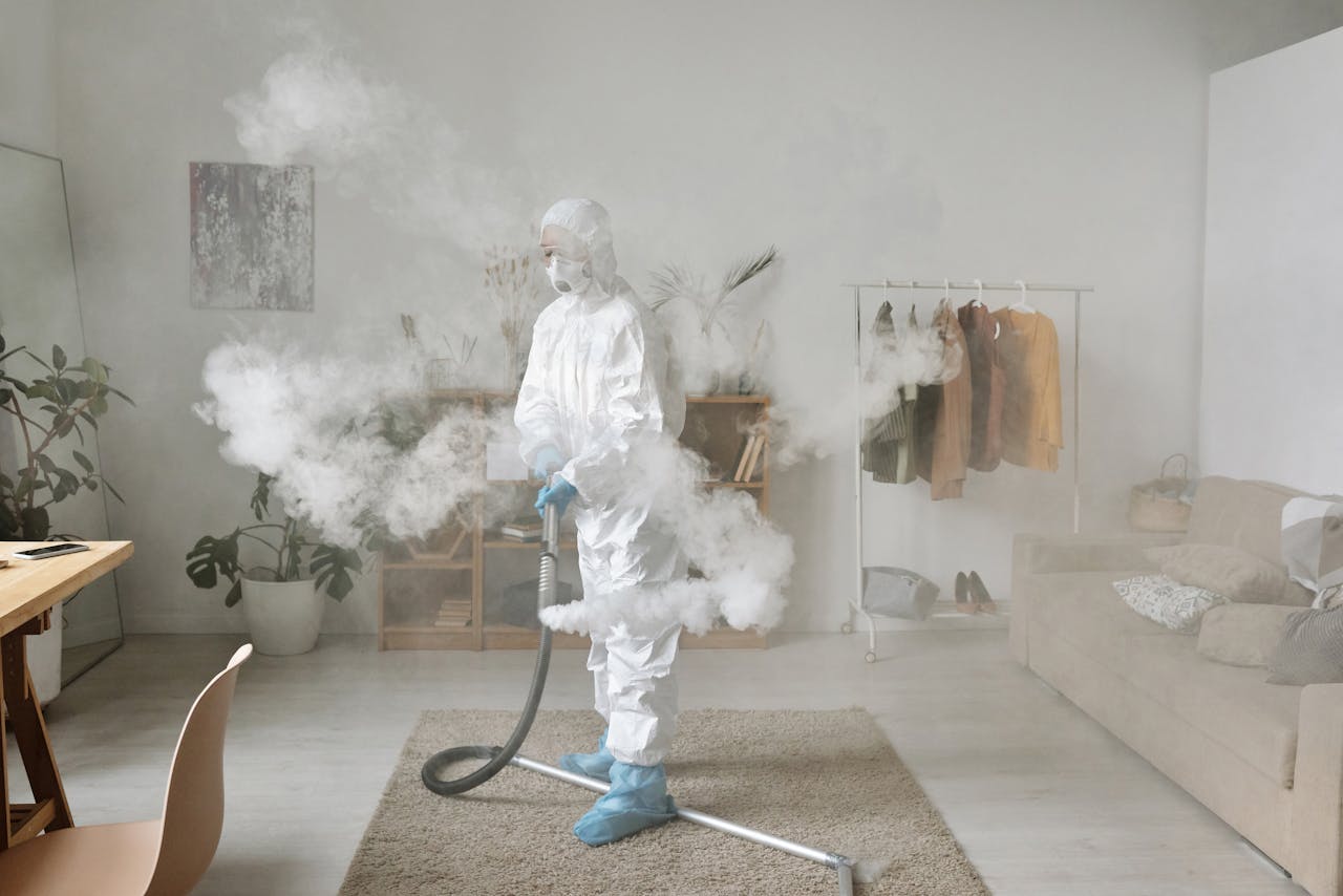 Person in protective suit disinfecting a stylish modern room with fumigation equipment.